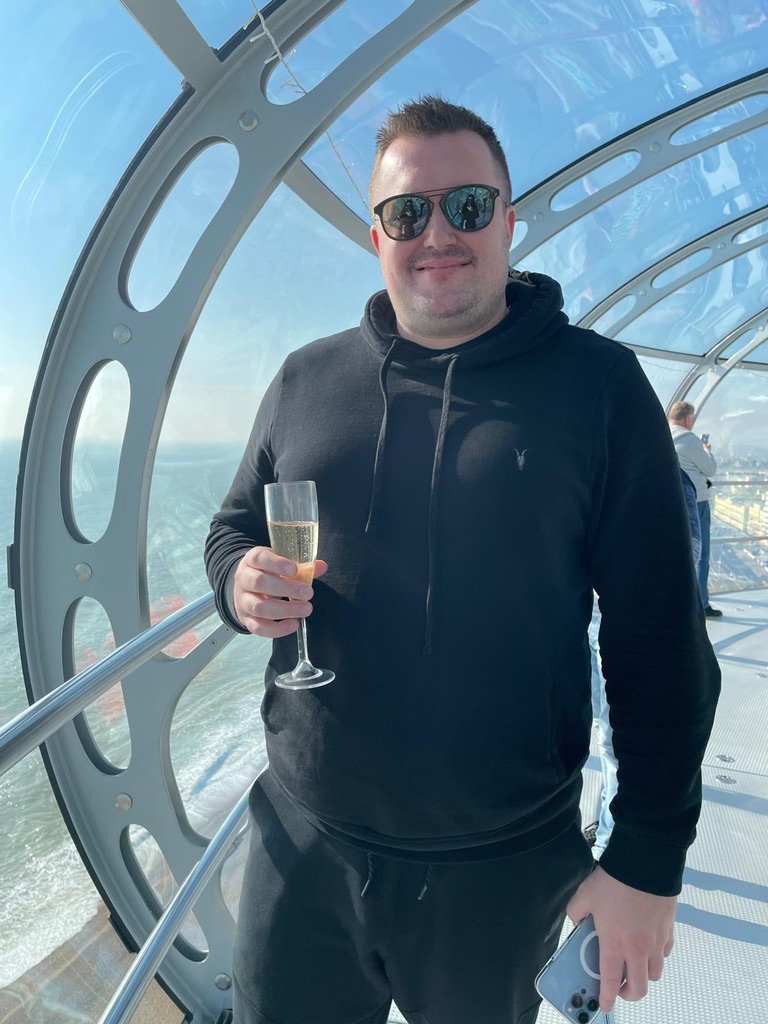 Danny Marshall smiling in an observation pod, holding a glass